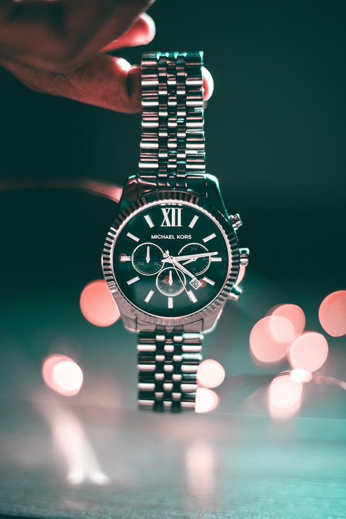 services-06 Silver Michael Kors wristwatch with Roman numerals and elegant design, highlighted by bokeh lights.